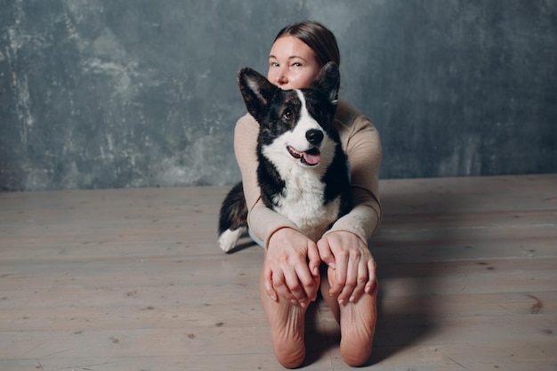 Adult mature woman doing yoga at home in living room with corgi dog pet