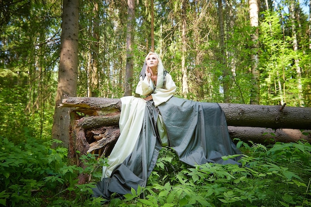 Photo adult mature woman in a green long fairy dress in forest photo shoot in style of dryad and queen of