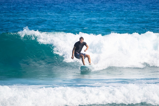 An adult rides a wave on a surfboard. Surfing.