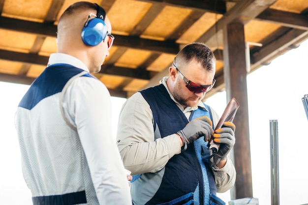 Adult shooter in sunglasses and gloves adjusts his gun with a hexagon before a competition