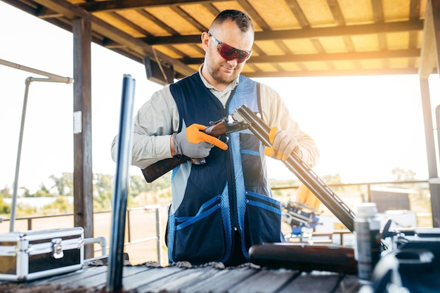 Adult trapshooter assembles his shotgun before starting to shoot