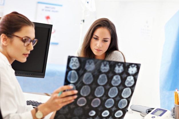 Adult woman discussing x-ray results during visit at female doctor's office