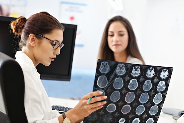 Adult woman discussing x-ray results during visit at female doctor's office