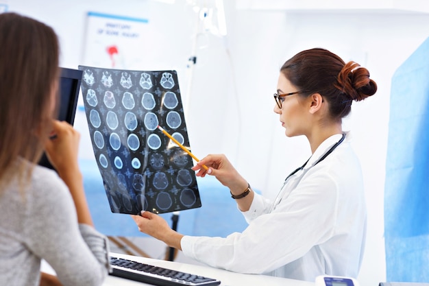 Adult woman discussing x-ray results during visit at female doctor's office