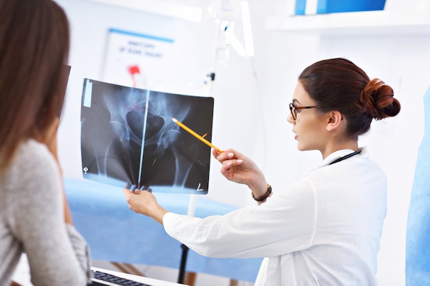 Adult woman discussing x-ray results during visit at female doctor's office