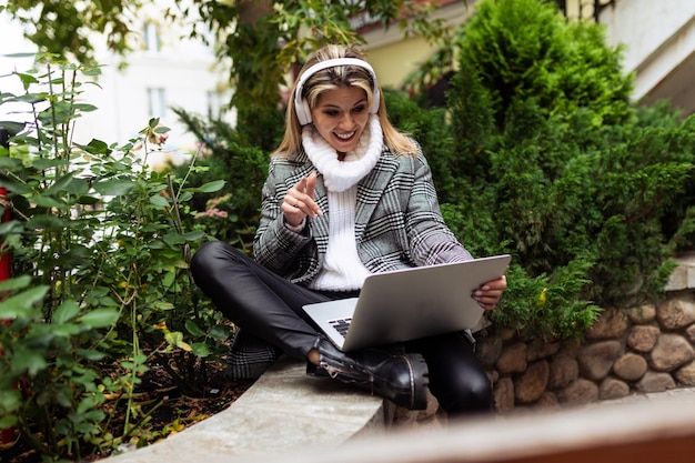 Adult woman freelancer working on a laptop online and listening to music in headphones on the