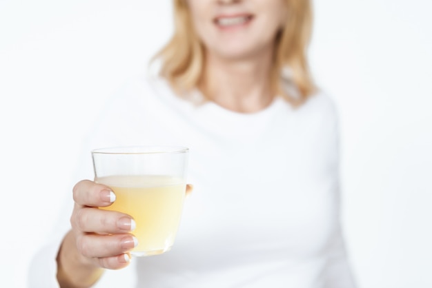 Adult woman holding medicine and looks into the camera.