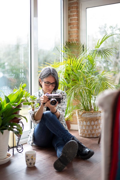 Adult woman at home using an analog photo camera Space for text