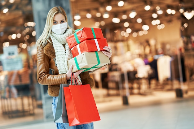 adult woman shopping in mall wearing a mask, coronavirus concept