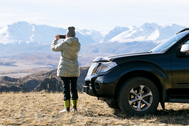 Adult woman travel autumn. Traveler woman photographing with phone beautiful landscape during her trip in mountains.