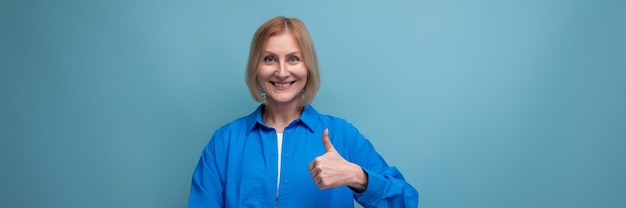 Adult woman with blond hair smiling on blue background with copy space