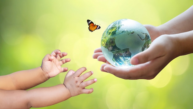 Adults are sending the world to babies. Concept day earth Save the world save environment. The world is in the grass