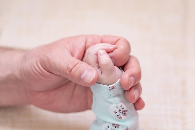 An adults hand holds a childs hand