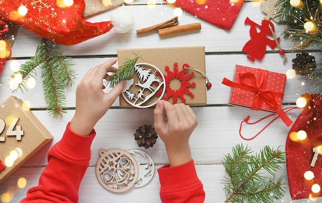 Advent calendarMerry Christmashild holds gift box in kraft paper next to other surprises in bags