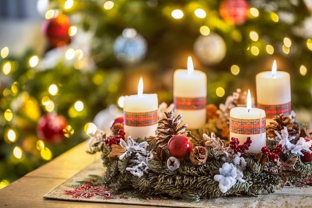 Advent wreath with four white burning candles christmas ball and decorations on a wooden background with festive atmosphere.