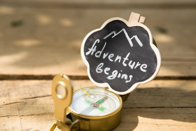 Adventure begins written on a small sign with compass Start your journey concept Wooden background