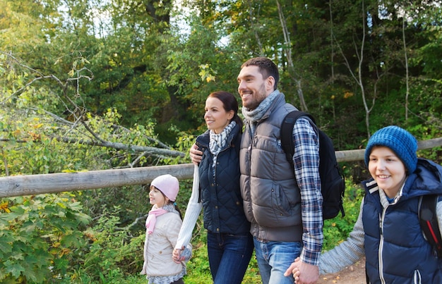 adventure, travel, tourism, hike and people concept - happy family walking with backpacks in woods