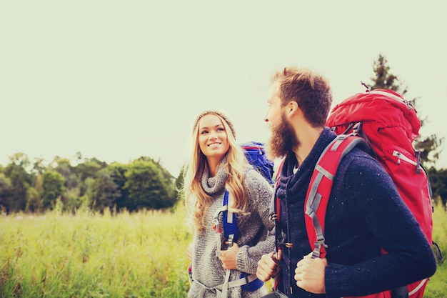 adventure, travel, tourism, hike and people concept - smiling couple walking with backpacks outdoors