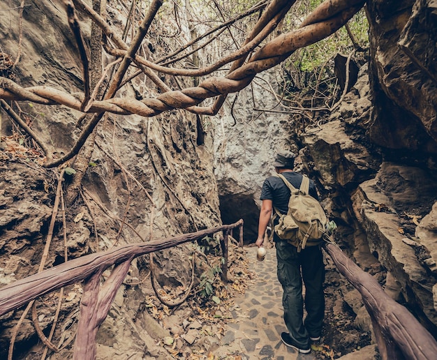 Adventurer holding binoculars for Bird watching and hiking trail in the forest and cave. Outdoor activity and recreation on summer vacation.