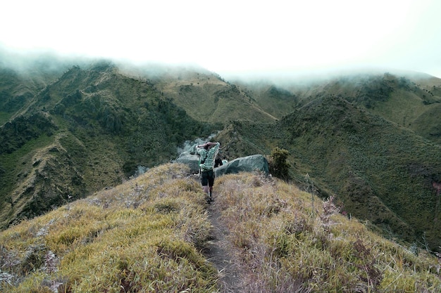 Adventurers Walk Towards Cloud-Covered Mountains