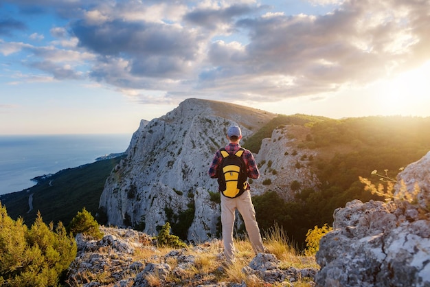 Adventurous man is on top of the mountain and enjoying the beautiful view during a vibrant sunset