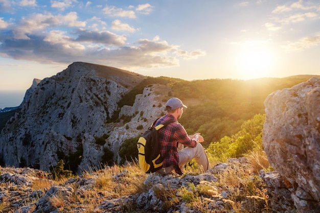 Adventurous man is on top of the mountain and enjoying the beautiful view during a vibrant sunset