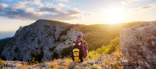 Adventurous man is on top of the mountain and enjoying the beautiful view during a vibrant sunset