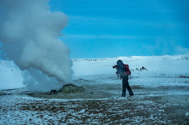 Adventurous photographer woman in winter in Iceland photographing in the Hverir or Namafjall Geothermal Area