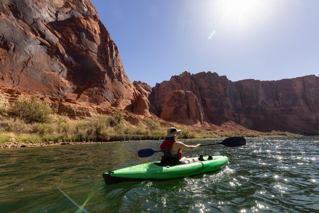 Adventurous woman on a kayak paddling in colorado river glen canyon arizona