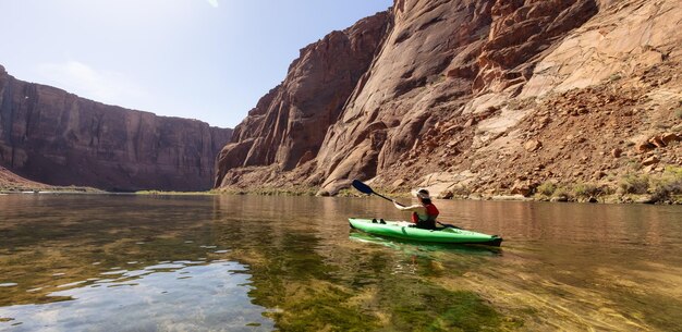 Adventurous woman on a kayak paddling in colorado river glen canyon arizona