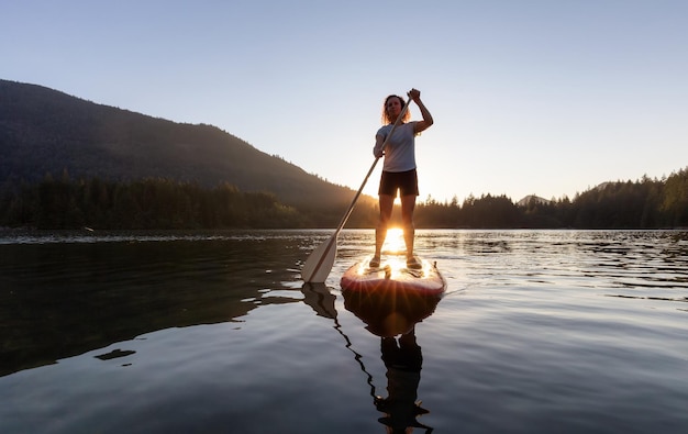 Adventurous woman paddling on a paddle board in a peaceful lake