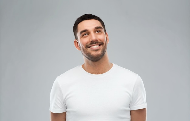 advertisement, idea, inspiration and people concept - happy smiling young man looking up over gray