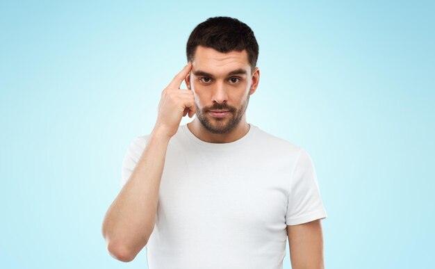 advertisement, idea, inspiration and people concept - man pointing finger to his temple over blue background