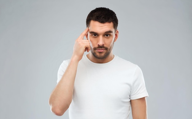 advertisement, idea, inspiration and people concept - man pointing finger to his temple over gray background