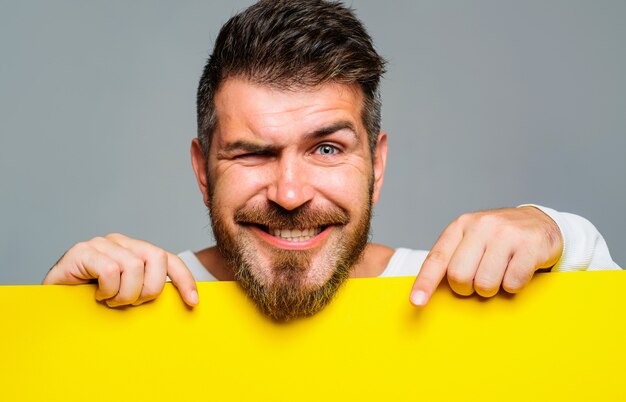 Advertising. Smiling bearded man with advertising banner. Happy male with empty placard or blank board with copy space.