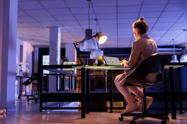 Advisor agent analyzing marketing graphs on laptop computer, working overtime at company growth report in startup office. Young entrepreneur typing financial statistics, planning strategy