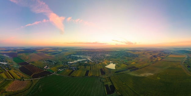 Aerial drone panoramic view of nature in Moldova at sunset. Village, wide fields, lake