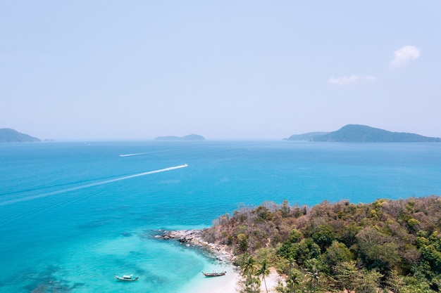 Aerial drone photo of a blue tropical lagoon surrounded by white sand of an exotic beach and palm trees. View from the top