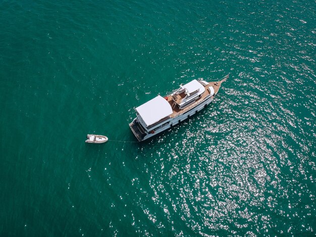 Aerial drone top view photo of luxury yacht with white rubber boat. Phuket. Thailand.