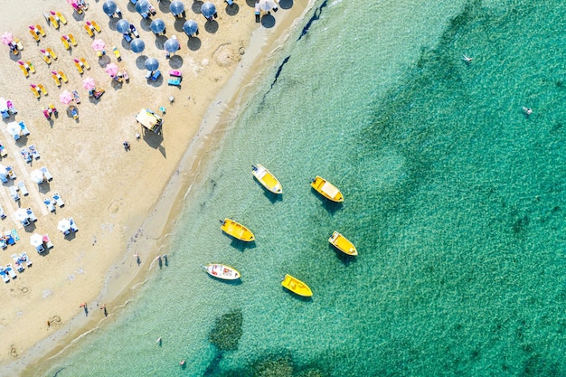 Aerial drone view of boats and beach with straw umbrellas with turquoise water Ionian sea Kefalonia Island Greece