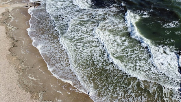 Aerial drone view flight over beautiful sea waves on sand beach with white foam