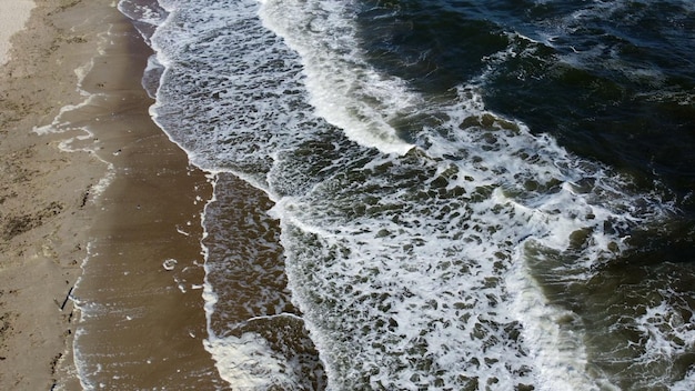 Aerial drone view flight over beautiful sea waves on sand beach with white foam