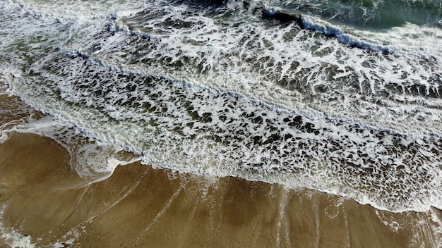 Aerial drone view flight over beautiful sea waves on sand beach with white foam