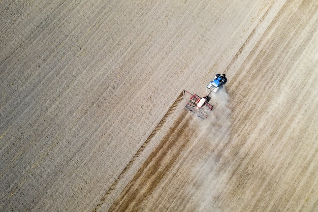 Aerial drone view with beautiful autumn landscape of working tractor on the harvest field. Agriculture concept.