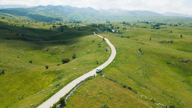 Aerial footage a car driving over Beautiful green mountain road in Pisce Montenegro