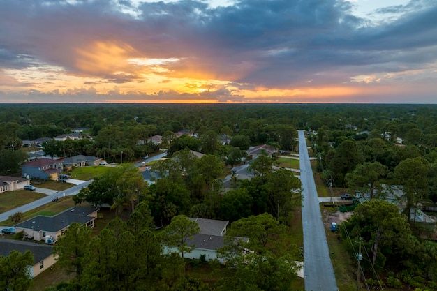 Aerial landscape view of suburban private houses between green palm trees in Florida quiet rural area at sunset