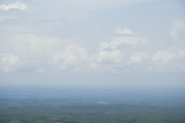 Aerial landscape view with a drone of meadow and cloudy sky horizon Beautiful natural view of green fields and sky Foggy weather drone shot of a hilly jungle area and sky horizon