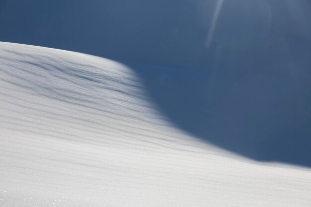 Aerial landscape of white snow forming a graphic texture play of light and shadows