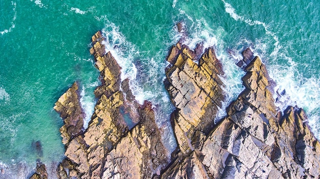 Aerial looking down on patch of rocky coasts in Maine with crashing waves