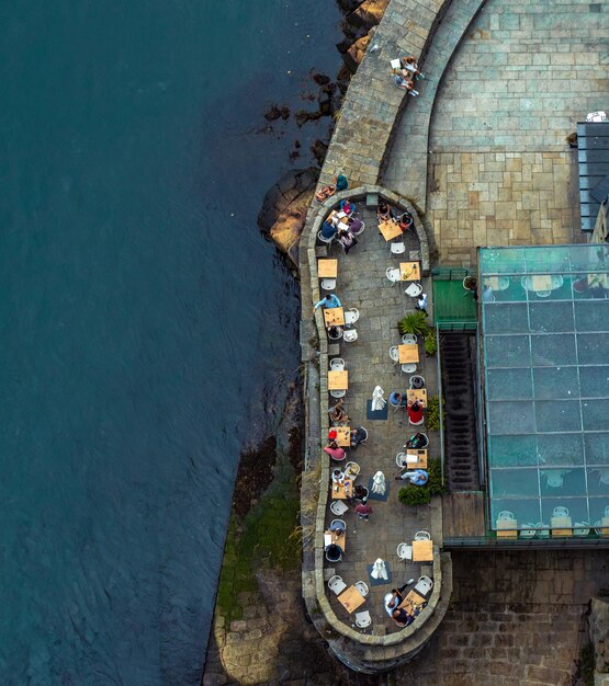 Photo aerial overhead view of people sitting at square tables and chairs on the terrace of a bar